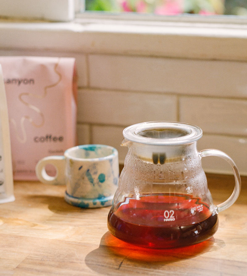 A clear glass coffee server on a wooden counter