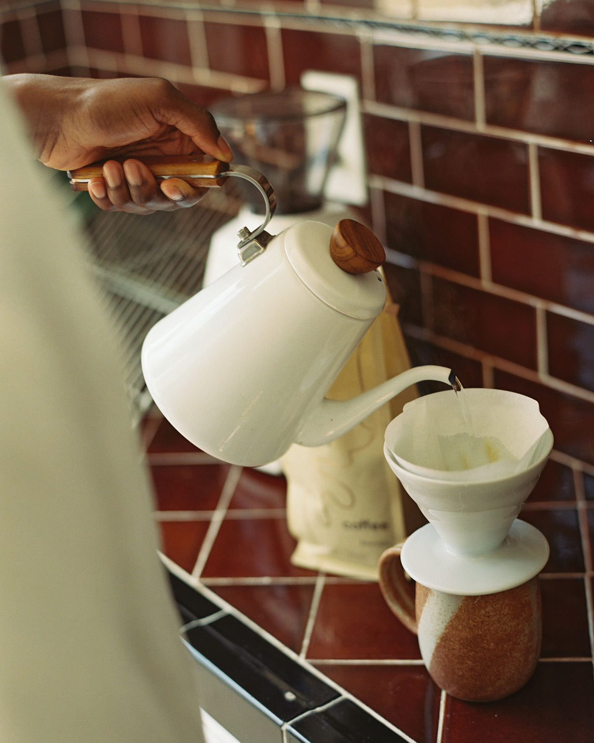 A white enamel kettle by Bona with a wooden handle making a v60 pour over