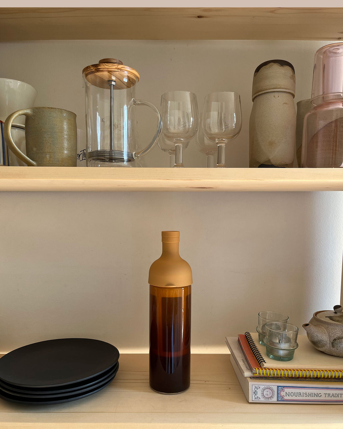A bottle for brewing cold brew coffee by Hario on a shelf with ceramics and filled with Canyon Coffee